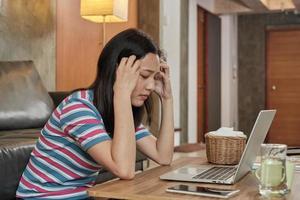 aziatische vrouw die thuis werkt is gestrest en hoofdpijn. foto