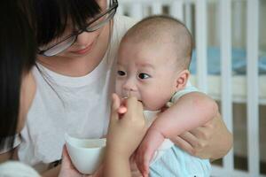 Aziatisch broers en zussen zorgzaam zus helpt voeden baby in een liefhebbend familie tafereel foto