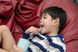 Aziatisch jongen poetsen zijn tanden Aan de leven kamer foto