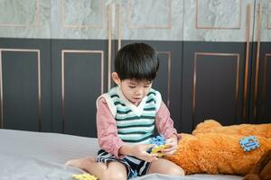 Aziatisch jongen spelen met decoupeerzaag puzzels Aan de bed blij foto