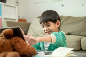 Aziatisch jongen aan het studeren online en aan het doen activiteiten Aan laptop foto