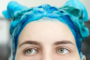 detailopname visie van meisje met blauw haar- en groot ogen met shampoo toegepast terwijl het wassen haar haar- na verven haar saffier haar- in schoonheid salon foto