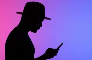 zelfverzekerd Afrikaanse Mens silhouet gebruik makend van mobiel telefoon terwijl staand naar neon achtergrond kopiëren ruimte en leeg ruimte voor tekst foto