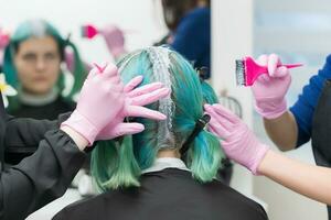 werkwijze van haar- verven in schoonheid salon. twee kappers van toepassing zijn verf naar haar- gedurende bleken haar- wortels foto