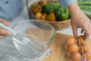 jong vrouw Koken in een helder keuken, hand- gemaakt gebarsten vers ei dooiers druipend in de schaal. voorbereidingen treffen ingrediënten voor gezond Koken. eigengemaakt voedsel foto