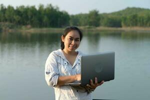 vrouw milieuactivist gebruik makend van laptop computer naar Vermelding natuurlijk water besmetting cheques. bioloog analyseren water test resultaten gebruik makend van technologie toepassing Aan laptop. water en ecologie concept foto