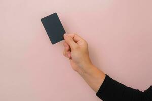 dichtbij omhoog van vrouw hand- Holding blanco zwart kaart geïsoleerd Aan roze achtergrond. foto