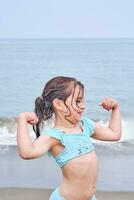 een meisje shows haar sterkte na zwemmen. foto