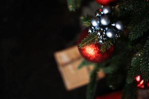 glanzende rode kerstbal die aan pijnboomtakken hangt foto