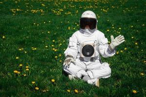 futuristische astronaut in een helm zit op een groen gazon tussen bloemen foto