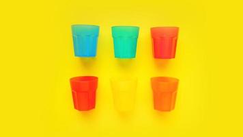 plastic glas van verschillende kleuren geïsoleerd op gele achtergrond foto