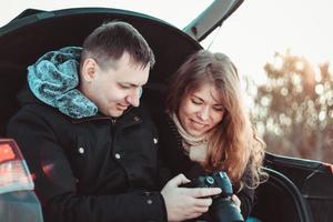 een man en een vrouw op de vrachtwagen van de auto. een gelukkig stel foto