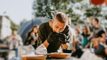 man die geniet van een straatvoedselfestival in de buitenlucht, een bier- en burgerevenement foto