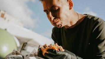 man die geniet van een straatvoedselfestival in de buitenlucht, een bier- en burgerevenement foto