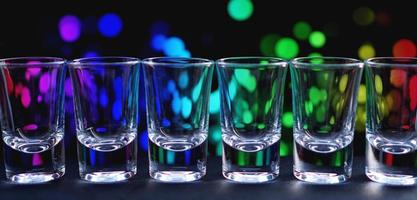rij schone glanzende glazen op een toog in een nachtclub foto