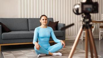 vrouwelijke blogger die thuis sportvideo opneemt. yoga houding foto