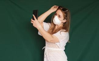 mooi meisje met medisch masker op het gezicht dat selfie neemt