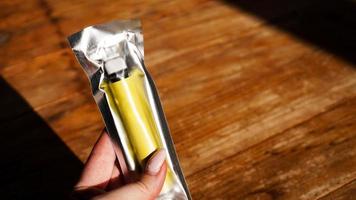 gele wegwerp elektronische sigaret in verpakking in vrouwelijke hand