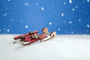 rood houten slee met sneeuwvlokken Aan een sneeuw schuiven. besneeuwd. winter pret foto