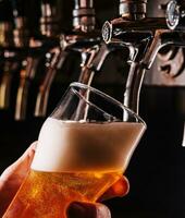 detailopname van barman hand- Bij bier kraan gieten een droogte lager bier foto