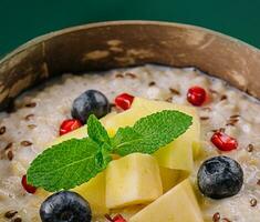 gezond ontbijt kom met pap met bosbessen, ananas en granaatappel foto