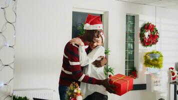 dolly in schot van werknemer verrast door collega met Kerstmis geschenk, knuffelen elkaar in feestelijk versierd kantoor. personeel lid opgewonden na wezen aangeboden Kerstmis Cadeau Bij werk, beven doos foto