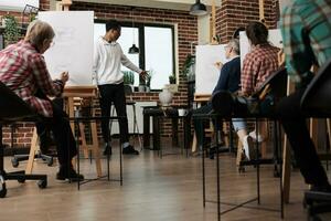 groep van mensen tekening met potloden Aan canvas, Bijwonen kunst klas. Afrikaanse Amerikaans vent leraar staand in klas tonen nog steeds leven object, uitleggen hoe naar trek vormen en proporties foto