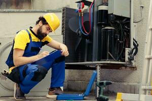 gekwalificeerd arbeider in opdracht voor buiten lucht conditioner jaar- onderhoud, op zoek voor gebroken intern onderdelen. bekwaam draadman aan het doen hvac systeem inspectie, schrijven verslag doen van Aan klembord foto