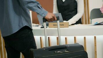 gast op reis met trolley Tassen Bij hotel, ontvangen toegang sleutel kaart Bij ontvangst na lang vlucht. Afrikaanse Amerikaans toerist Aan vakantie Bij vijf ster vakantie toevlucht. dichtbij omhoog. handheld schot. foto