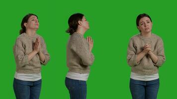 religieus geestelijk meisje poseren met gebed handen teken in studio, bidden naar god naar te ontvangen geluk en fortuin. jong volwassen uitdrukken geestelijkheid en geloof, staand in stilte Aan groene scherm. foto