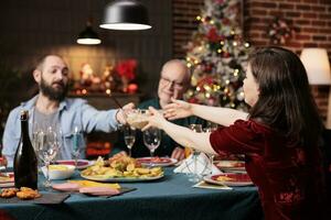 mensen aan het eten feestelijk voedsel Bij diner, vieren Kerstmis vooravond samen en voorbijgaan maaltijd borden in de omgeving van de tafel. gelukkig familie vergadering Bij huis naar vieren Kerstmis vakantie evenement, partij feest. foto