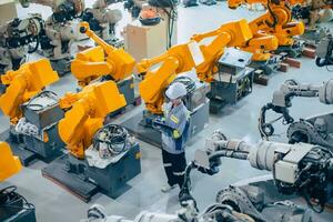 ingenieur personeel arbeider werken in groot machine bijeenkomst fabriek. werknemer werk tellen inspectie voorraad van machine robot arm. foto