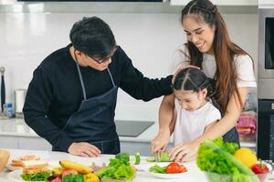 Aziatisch familie mensen genieten onderwijs kinderen koken voedsel gebruik makend van mes voor gezond Bij huis foto