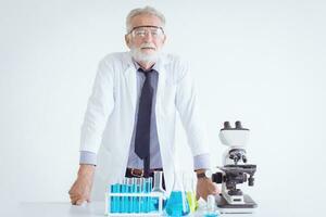 portret dokter senior ouderen wetenschapper chemicus staand in chemisch wetenschap ronde met microscoop foto