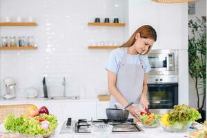 mooi jong vrouw proberen koken gezond voedsel salade groenten mengen Bij huis keuken foto