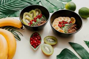 acai kom met gezond bessen, kiwi, avocado Aan tropisch palm blad Aan wit achtergrond. gezond vegetarisch voedsel. foto