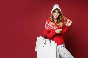 glimlachen vrouw in winter kleding poseren in studio Aan rood achtergrond. foto