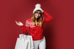 glimlachen vrouw in winter kleding poseren in studio Aan rood achtergrond. foto