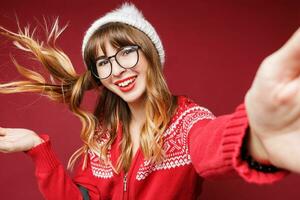 glimlachen vrouw in winter kleding poseren in studio Aan rood achtergrond. foto