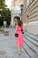 mooi vrouw in roze jurk poseren Aan de straat. foto