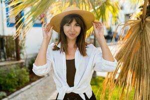 zomer vportret van mooi brunette vrouw in rietje hoed poseren buitenshuis. foto