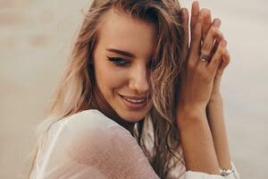 buitenshuis zomer portret van mooi gelukkig blond vrouw chillen Aan de strand in de buurt oceaan. lichaam zorg concept. foto