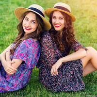 zonnig zomer portret van twee vrolijk meisjes Tweelingen zittend Aan groen weide en genieten tijd samen. foto