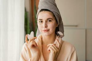 huid zorg. vrouw poetsen klei modder masker naar haar gezicht. poseren Aan de modern woonkamer.cosmetisch procedures. foto