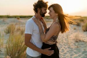 mooi paar in liefde poseren Aan tropisch strand. knap Mens met baard knuffelen zijn vriendin. tropisch boho kleding. foto