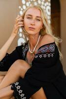 mode foto van mooi blond vrouw in boho zomer kleding poseren buiten. vervelend elegant ketting. tropisch humeur.