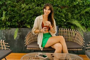 vrolijk brunette vrouw genieten lieverd limonade en zittend in modern cafe. foto