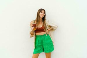 zomer portret van elegant brunette vrouw genieten lieverd limonade en poseren Aan wit achtergrond. foto