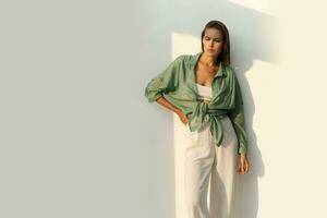 modieus vrouw poseren over- wite achtergrond. gewoontjes kleding. groen linnen blouse . wit Bijsnijden top en broek. vol lengte. foto