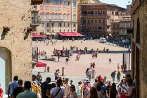 Siena , Italië-augustus 10, 2020-toeristen en souvenir winkels in Siena in de buurt de campo plein gedurende een zonnig dag foto